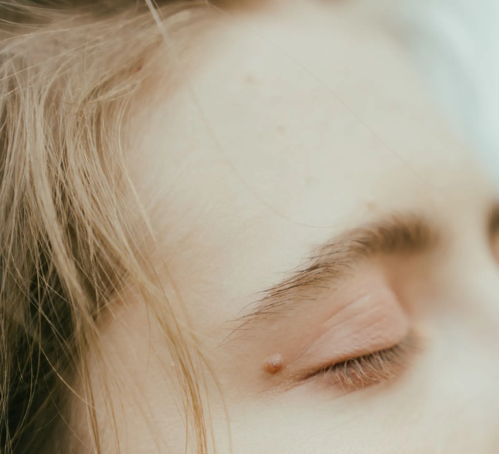 Detalhe de um rosto com os olhos fechados e expressão relaxada.