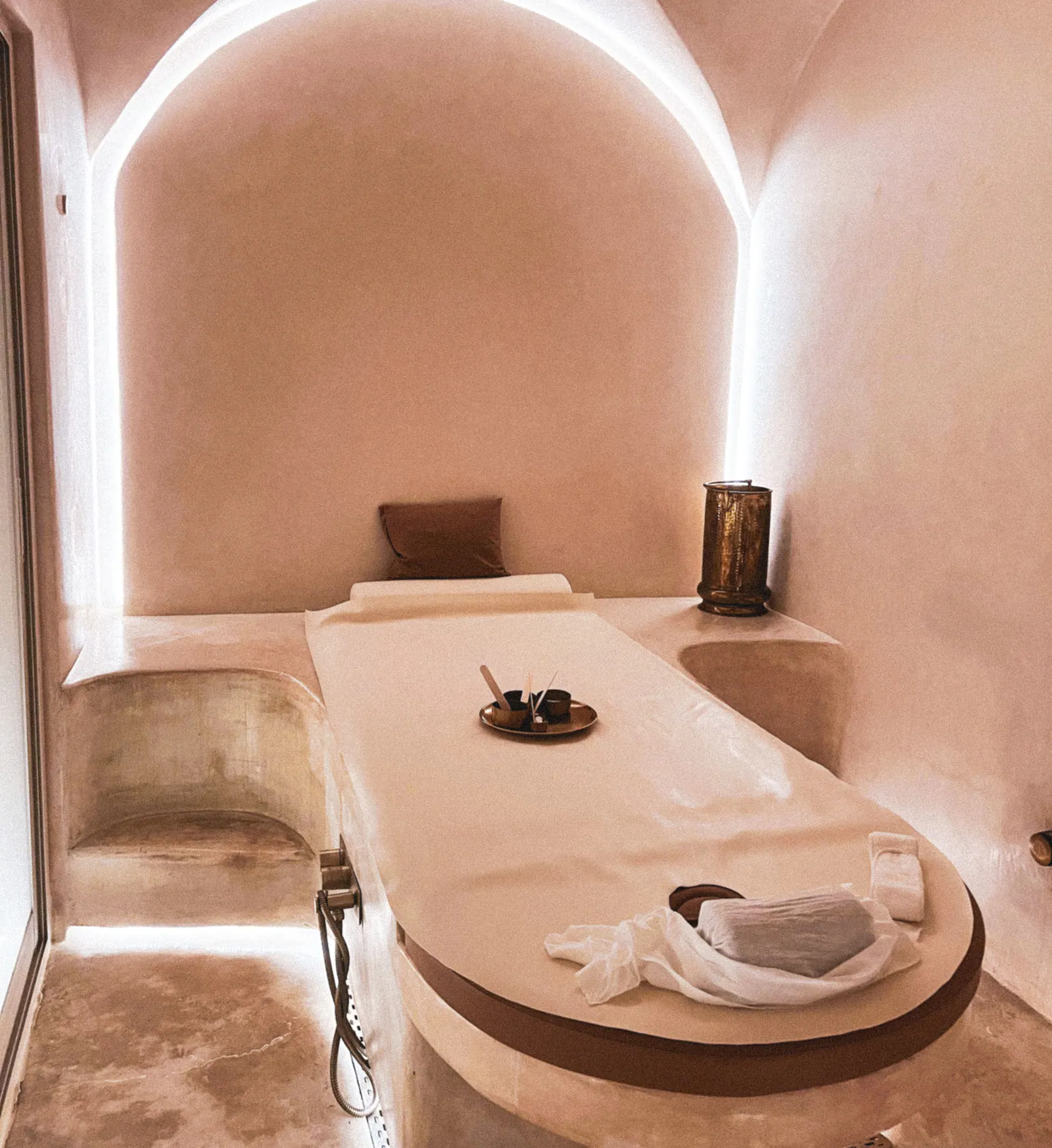 Ambiente de spa em tons quentes, com maca e iluminação indireta.